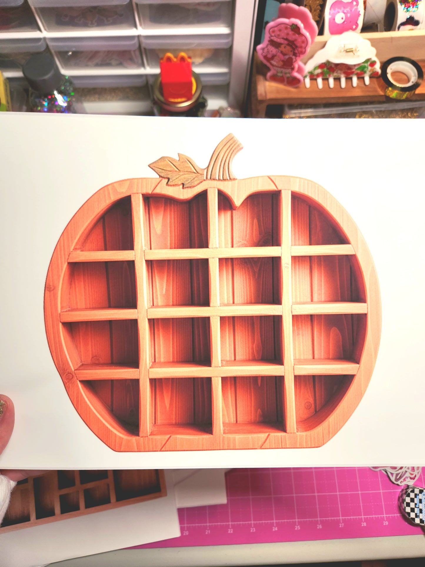 Wooden apple-shaped organizer on a white surface with a pink cutting mat in the background.