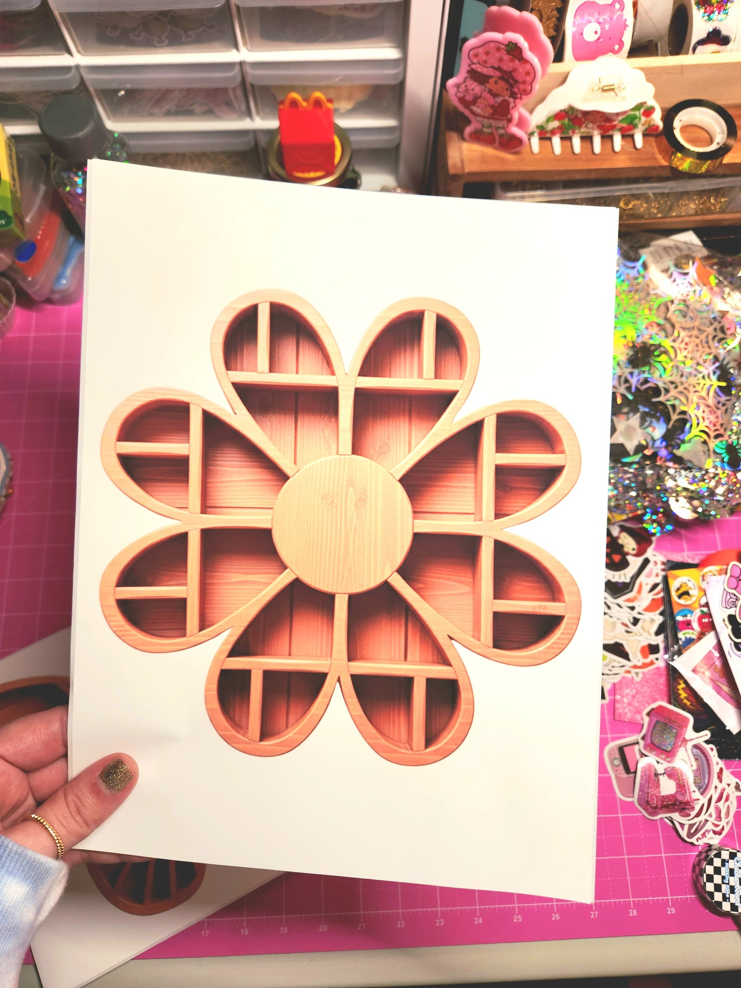 Wooden flower-shaped object on a white card held by a hand, with a colorful background.