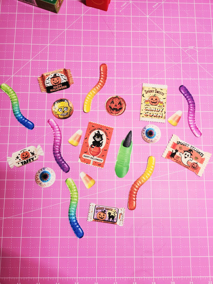 Assorted Halloween-themed gummy candies on a pink grid background