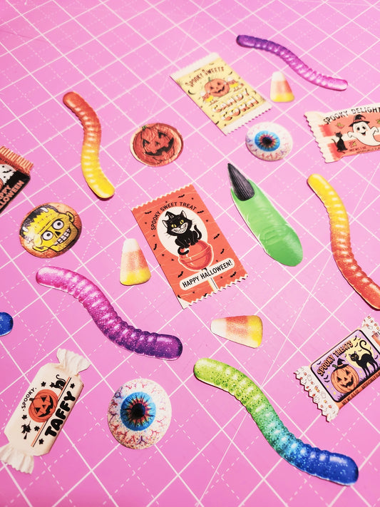 Halloween-themed candies and toys on a pink grid background