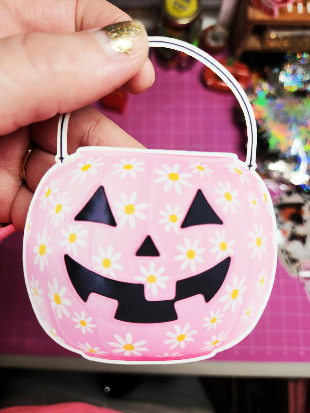 Pink Halloween-themed candy bag with a pumpkin face design held by a hand.