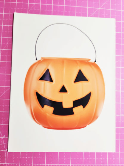 Halloween candy bucket with jack-o'-lantern face on a pink cutting mat