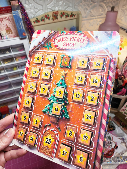Advent calendar with Christmas design held by a hand, in front of a blurred craft store background.