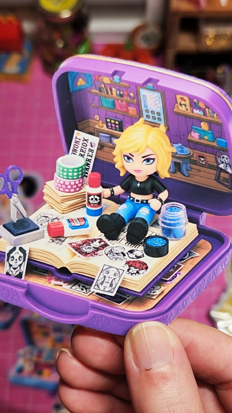 Small figurine with accessories in a purple case held by a hand against a colorful background