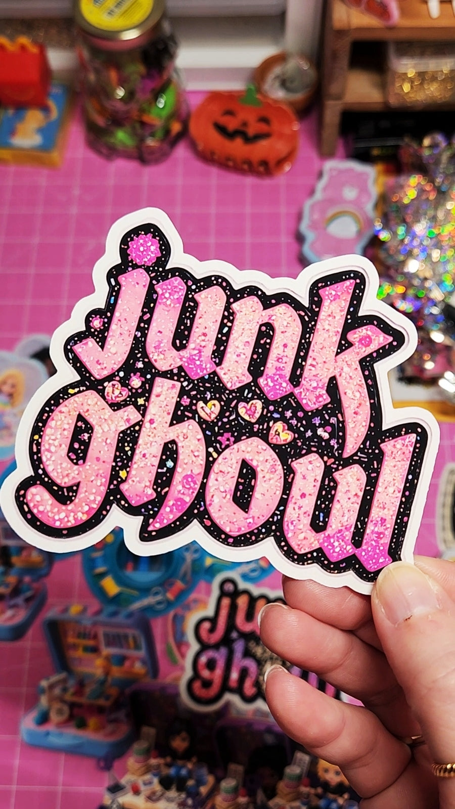Sticker with 'junk show' text held over a colorful background