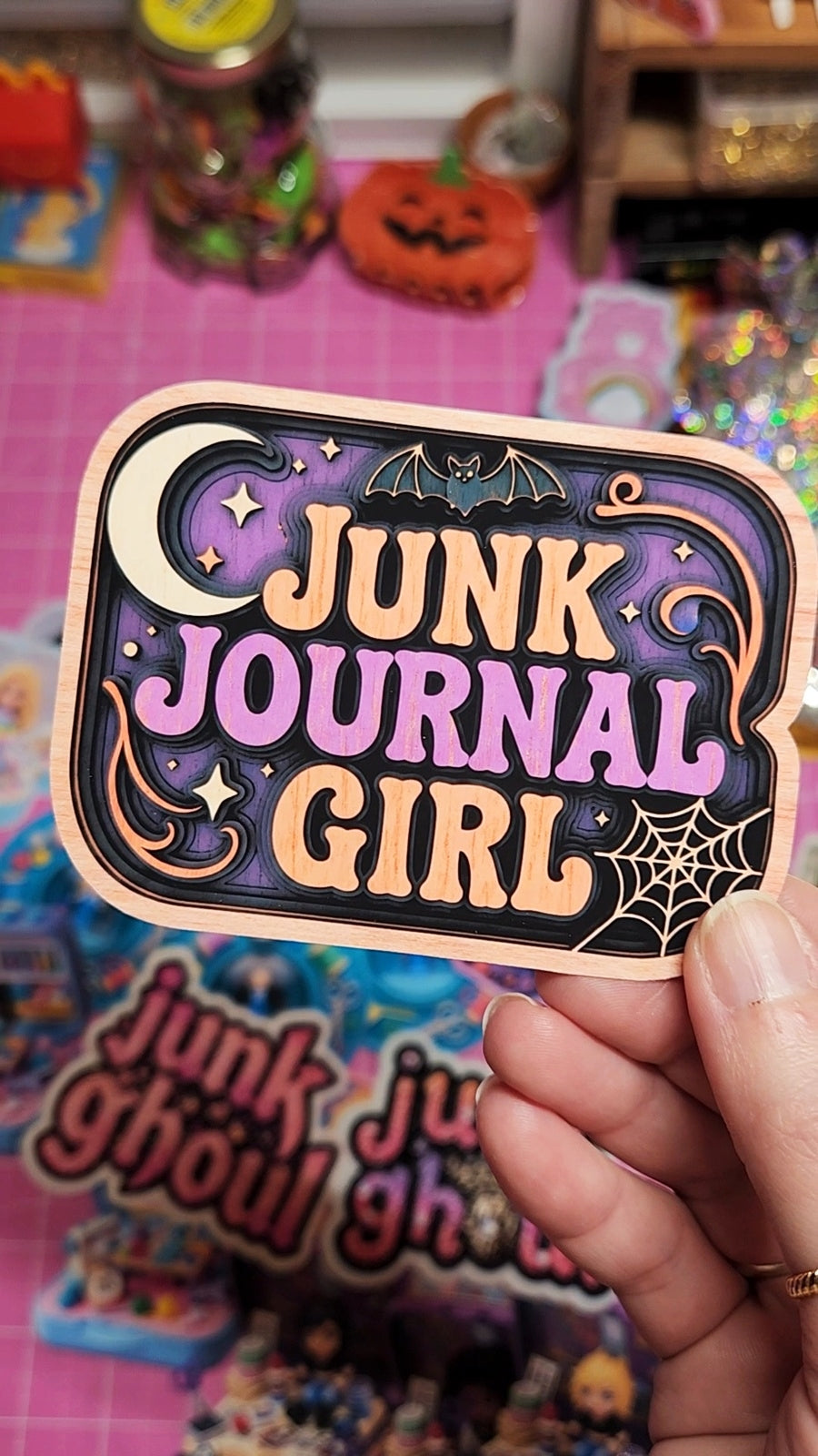 Sticker with 'Junk Journal Girl' text held by a hand on a colorful background
