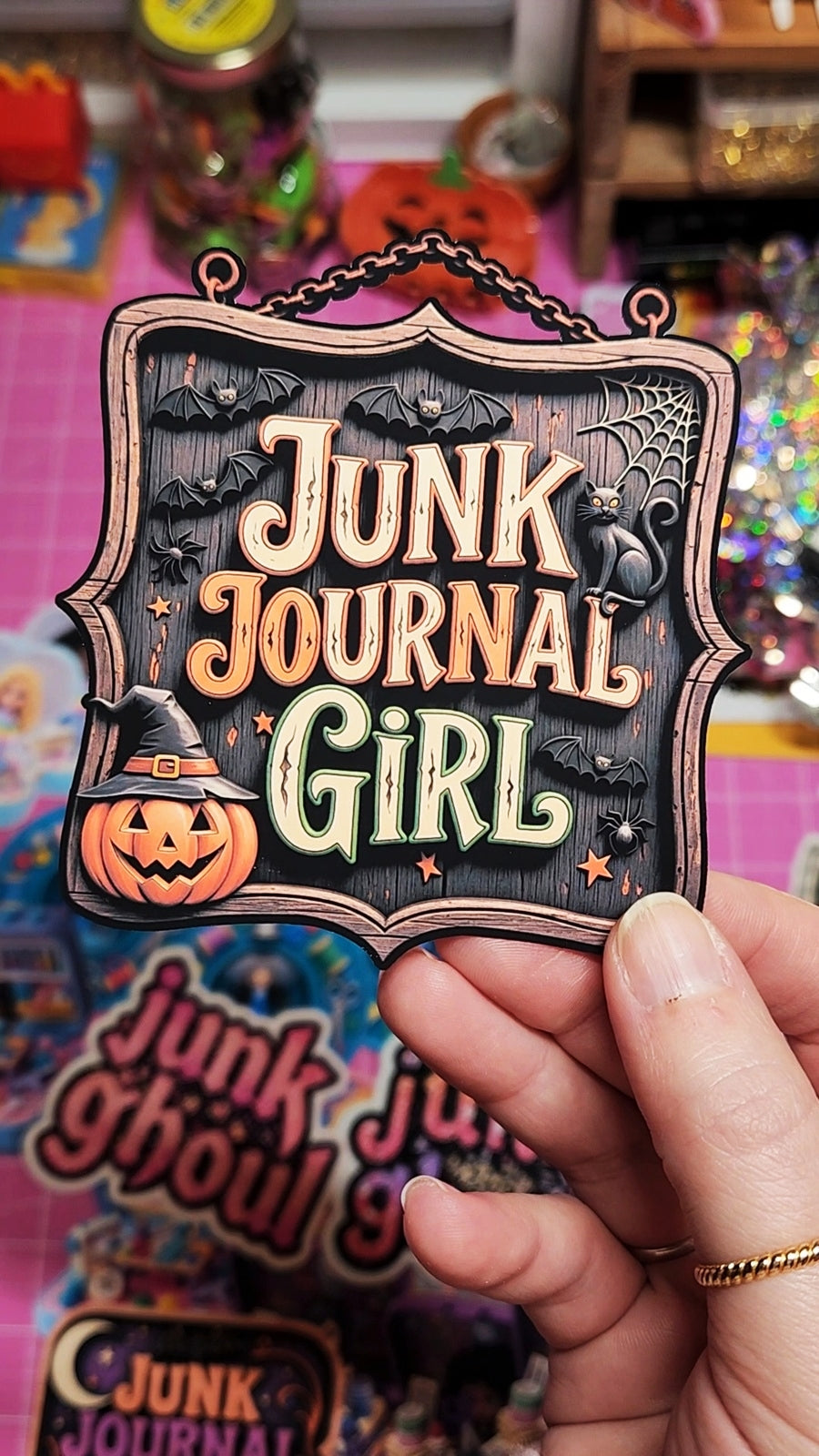 Hand holding a 'Junk Journal Girl' product with Halloween-themed design against a colorful background.