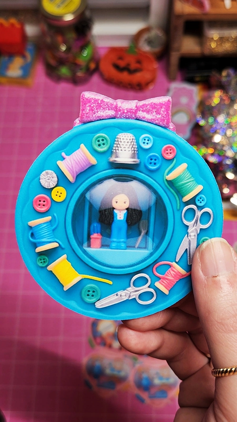 Toy sewing set with figures and tools on a pink background