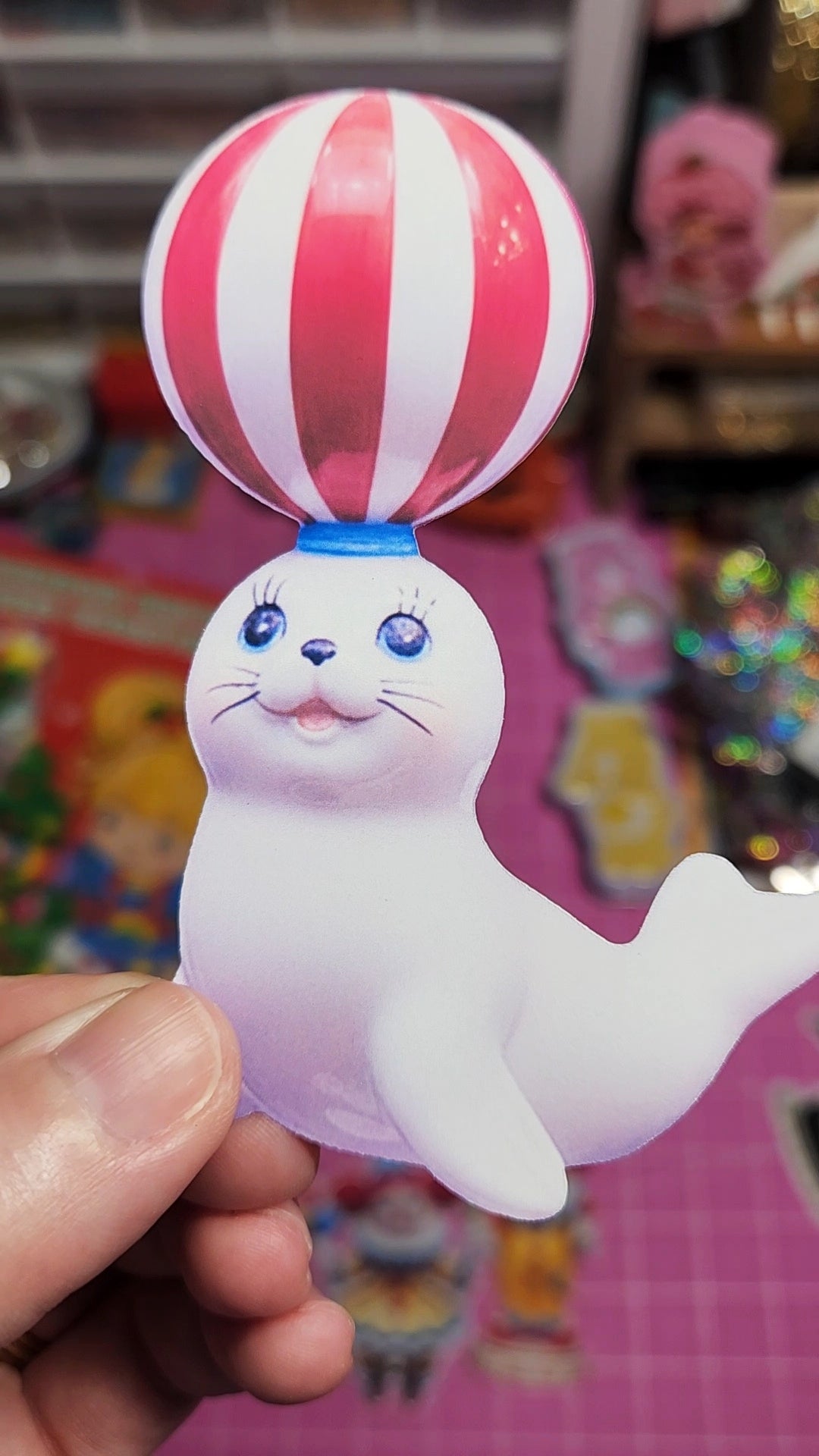 Toy figure of a seal with a striped balloon on a colorful background