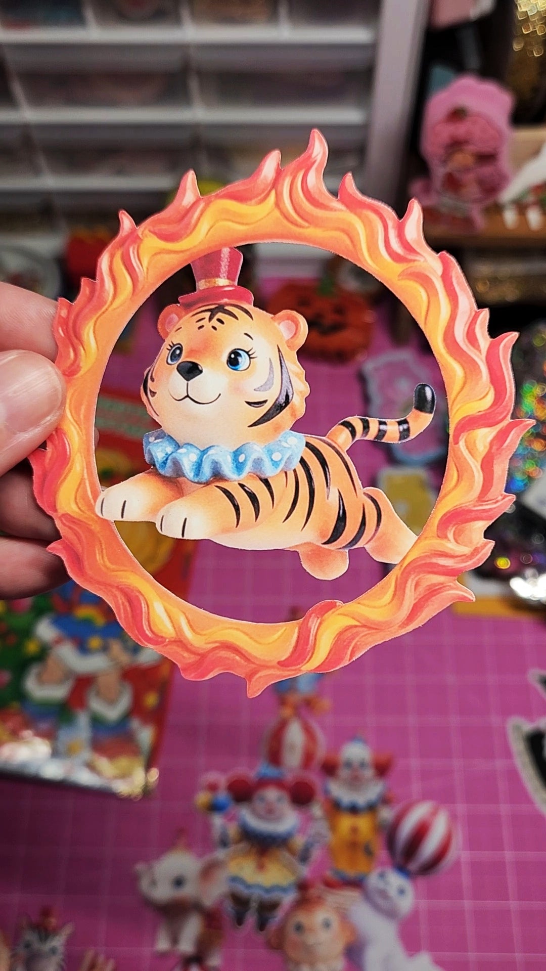 Toy tiger figure inside a circular frame with flames, held against a colorful background.