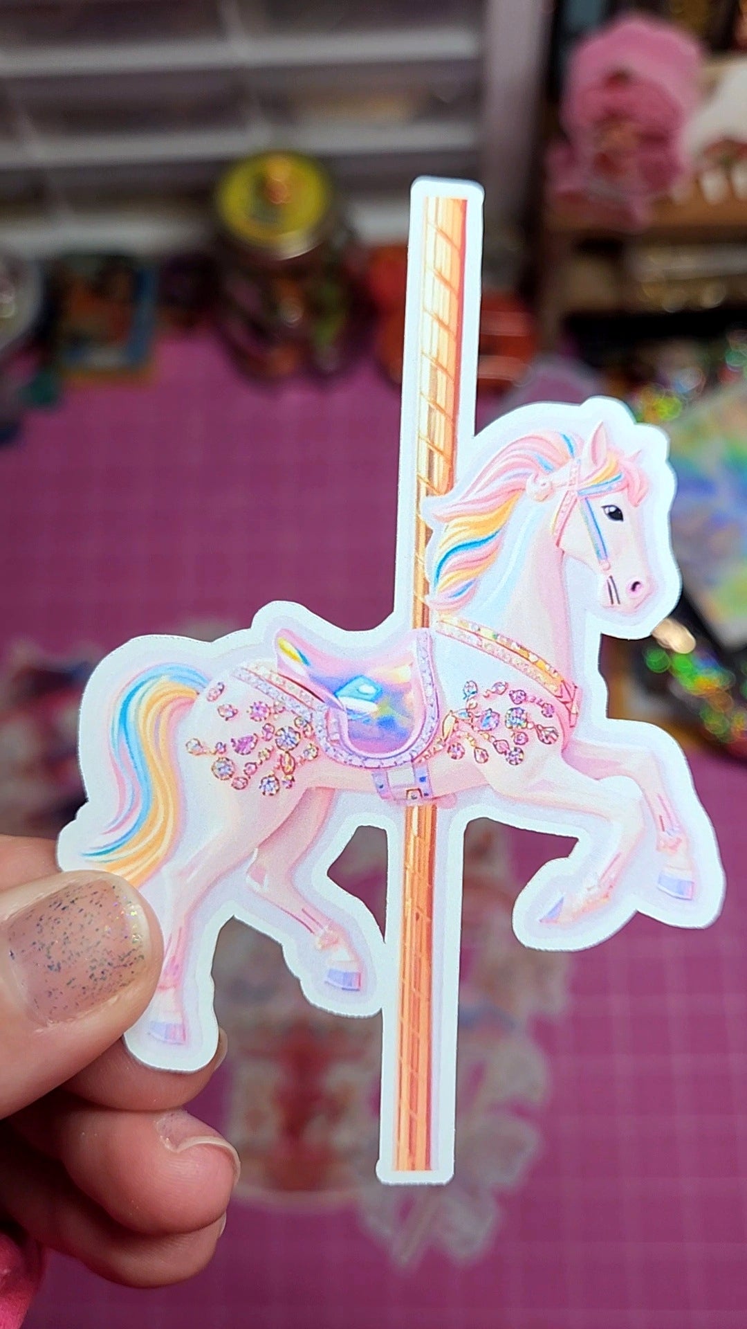 Sticker of a carousel horse held by a hand with a colorful background