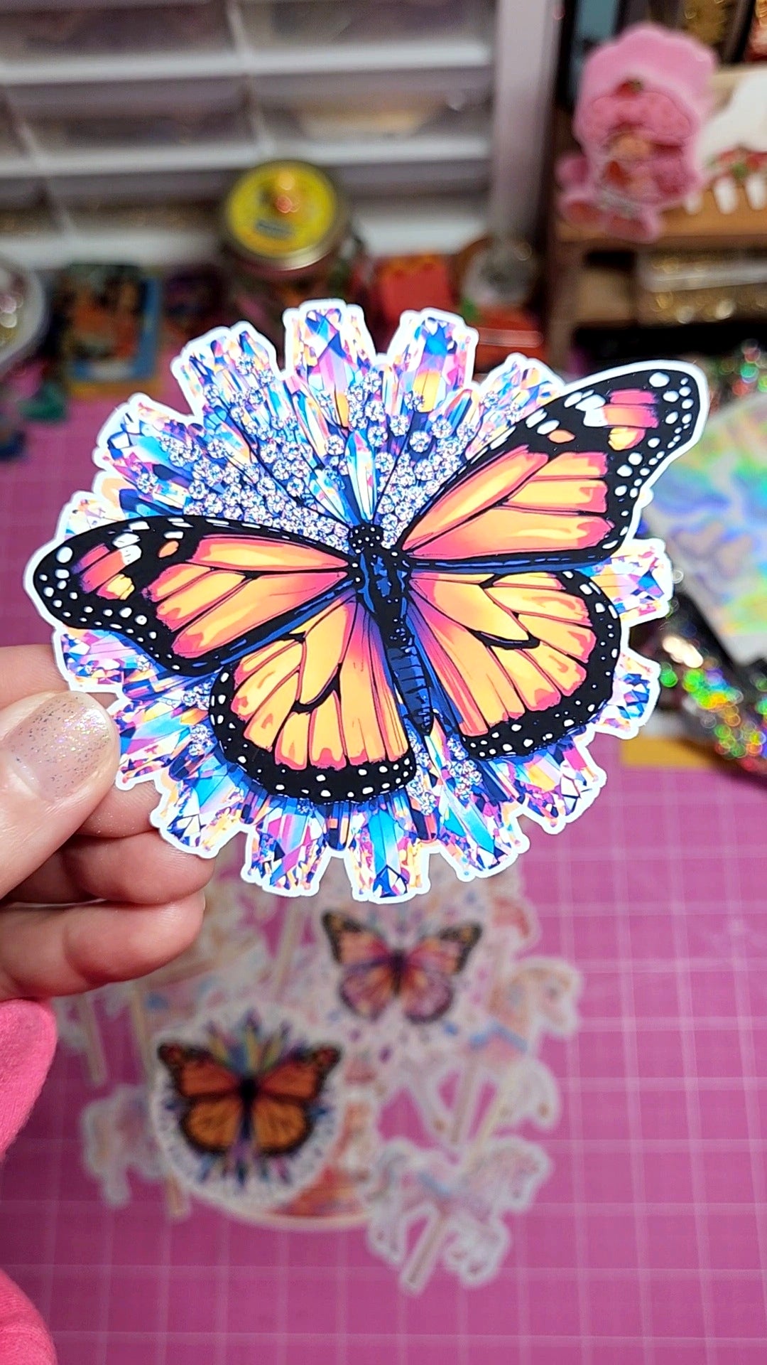 Butterfly sticker held by a hand with a colorful background