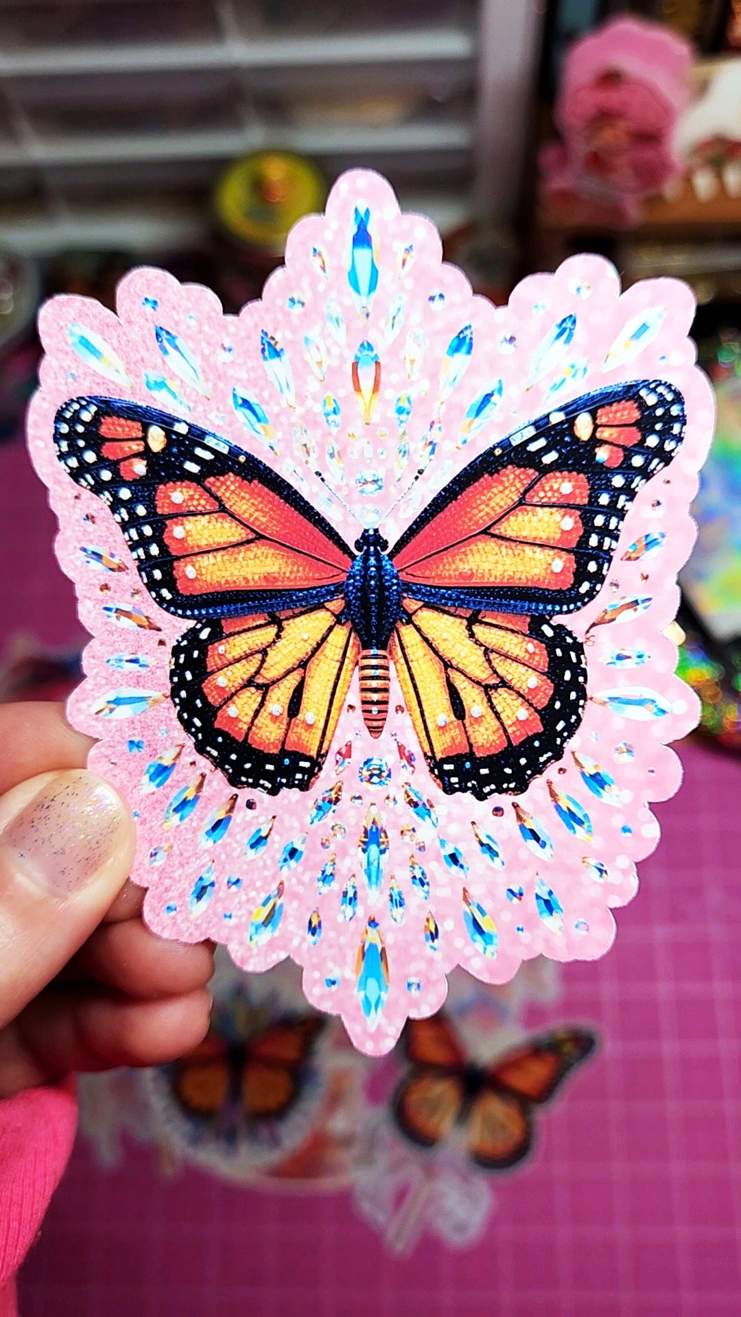 Butterfly design on a pink lace background held by a hand.