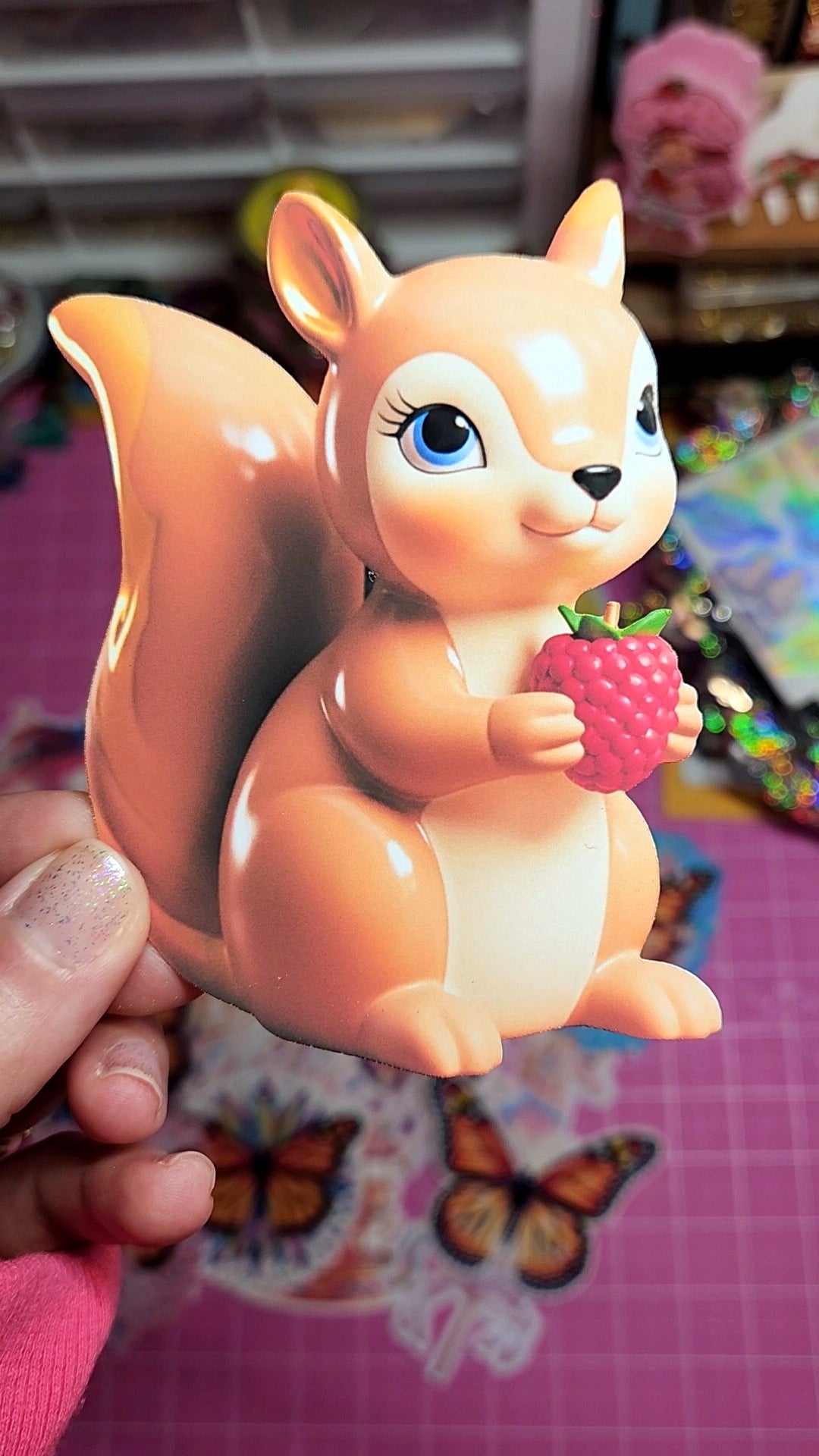 Squirrel-shaped night light held by a hand on a colorful background