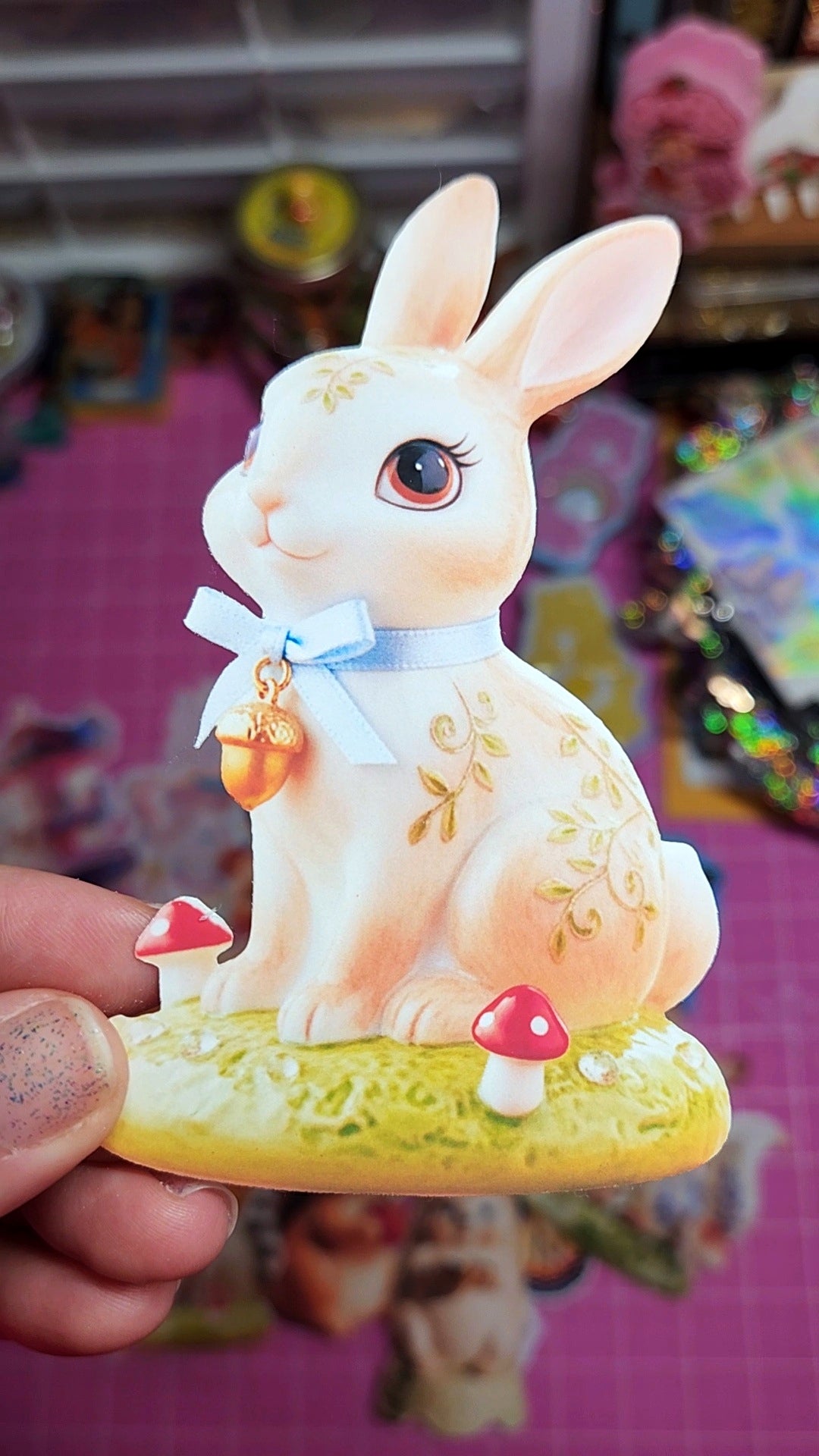 Decorative figurine of a rabbit with a bow tie held in front of a colorful, blurred background.