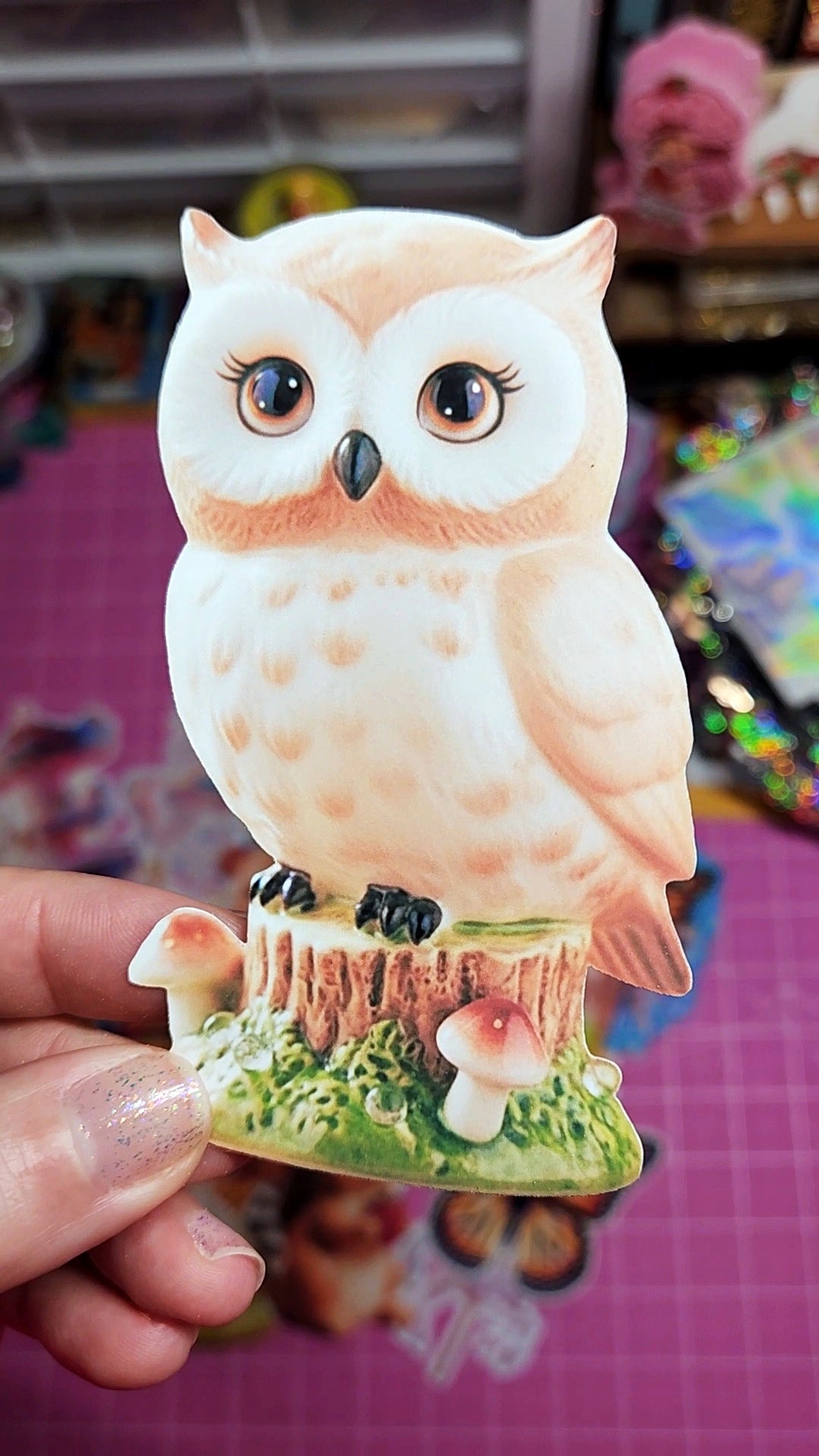 Decorative owl figurine held by a hand with a colorful background