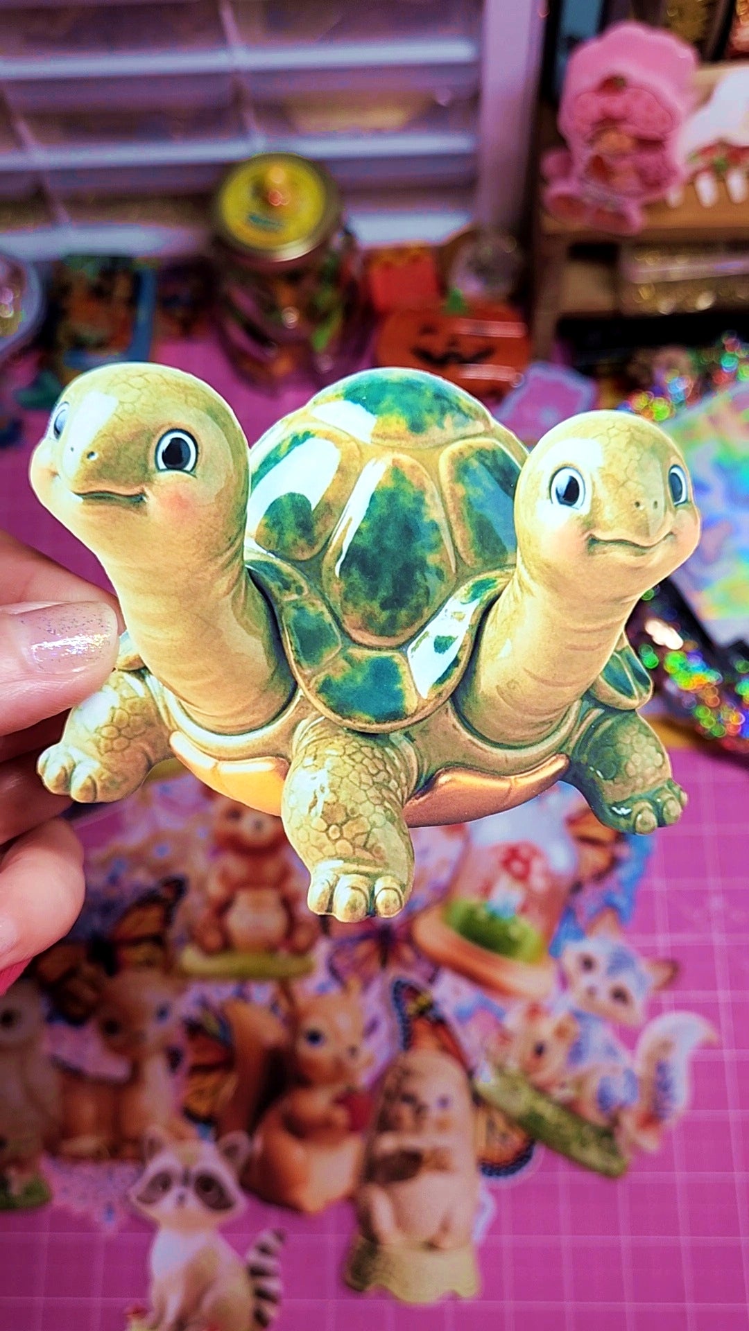 Two turtle figurines held against a colorful background with cartoon characters.