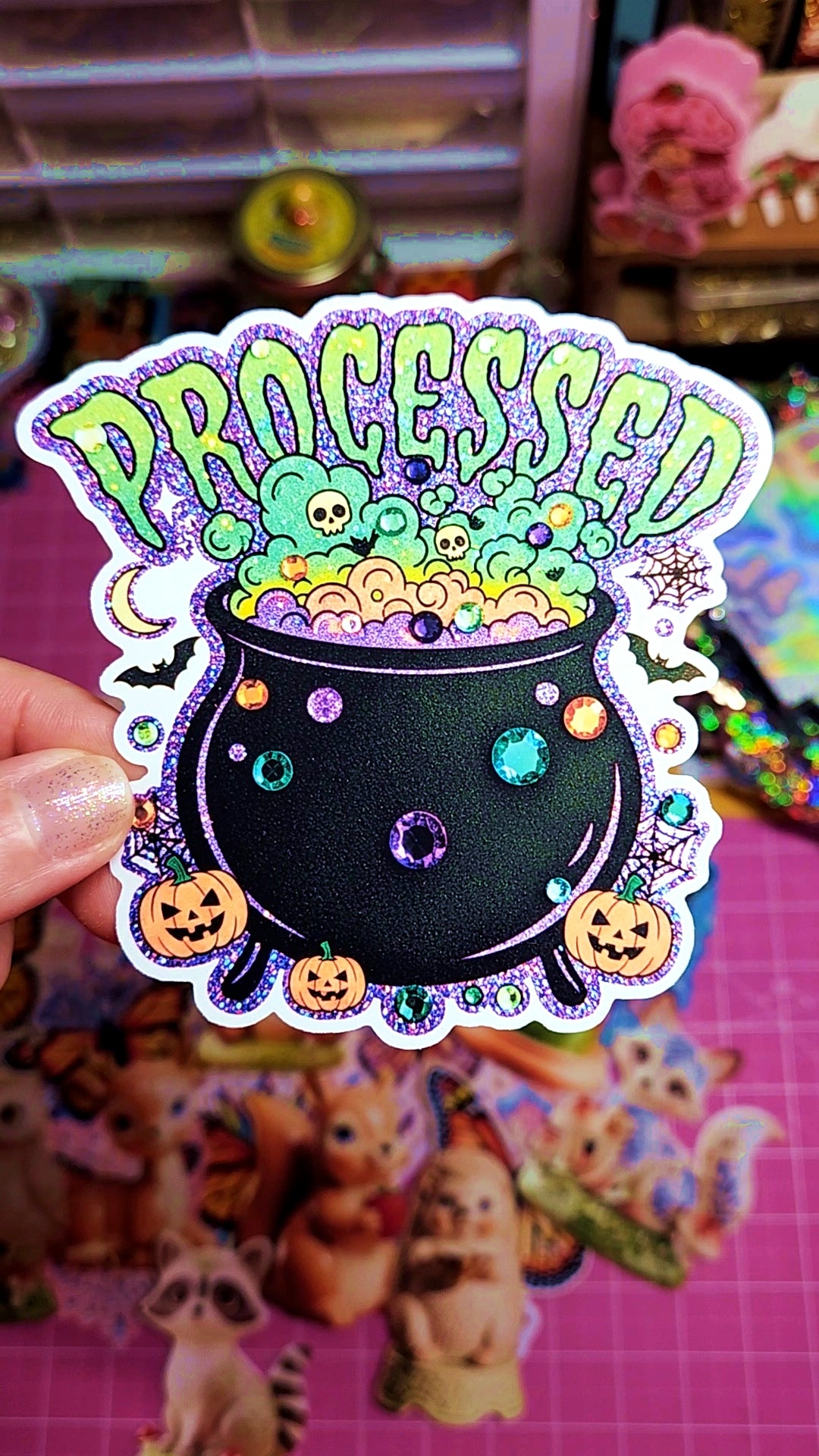 Sticker with 'Processed' text and Halloween-themed design held by a hand on a colorful background.