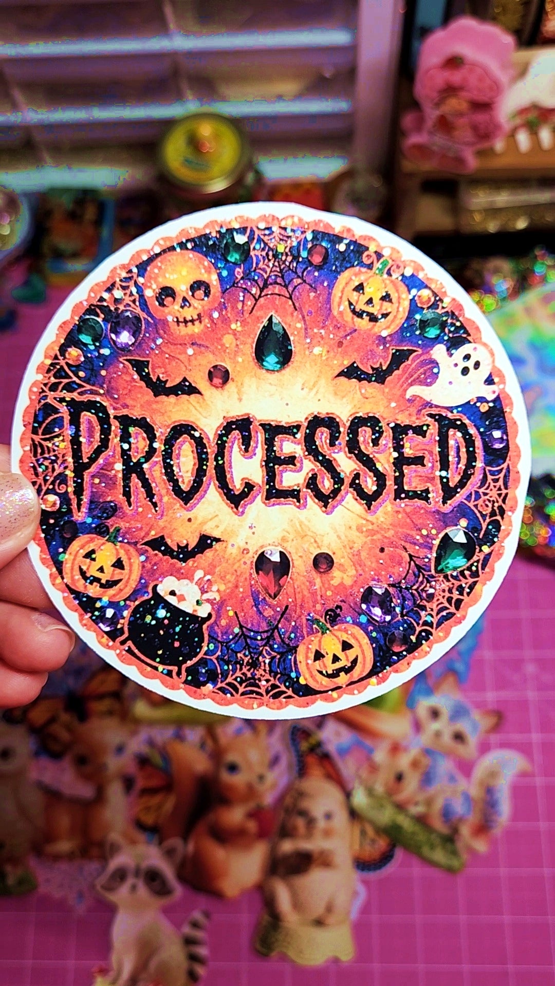 Halloween-themed sticker with 'PROCESSED' text held in front of a colorful background.