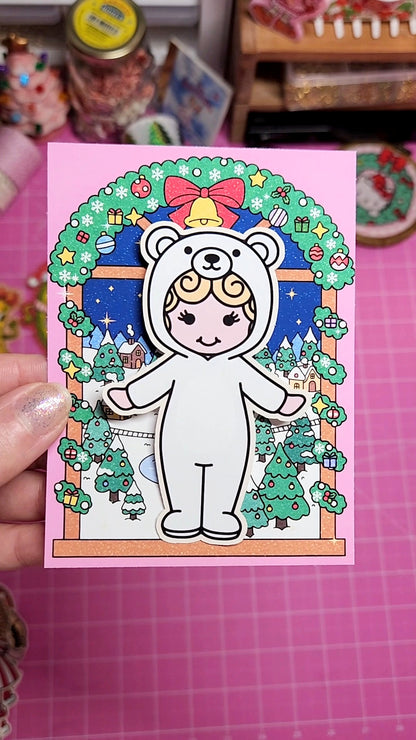 Illustration of a character in a white bear costume with festive decorations on a pink card.