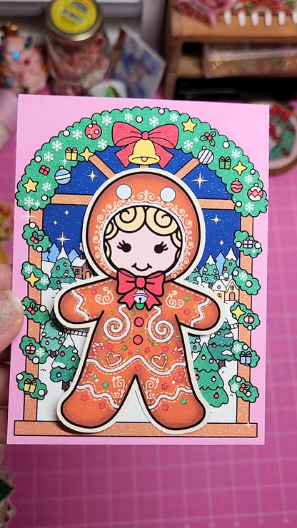 Colorful gingerbread man illustration on a pink card with decorative border.