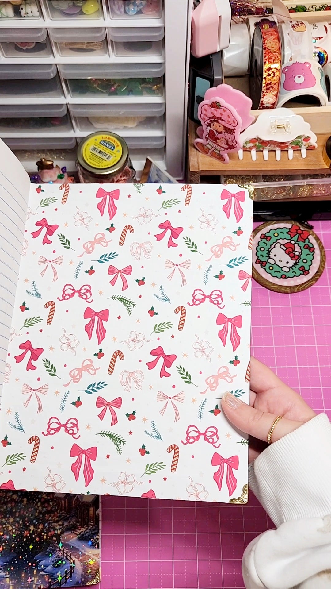 Sheet of paper with festive bow and candy pattern held by a hand in a craft room.