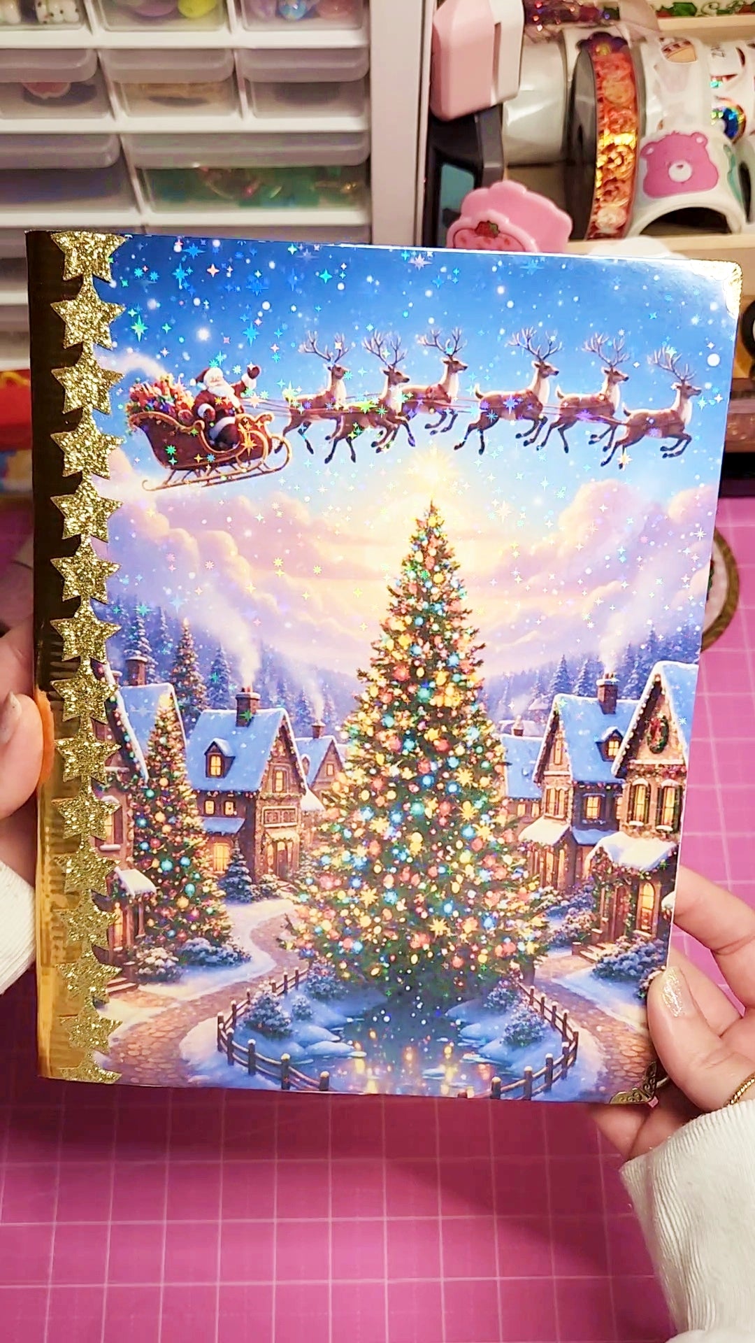 Decorative Christmas card with Santa Claus and reindeer in a snowy village scene.