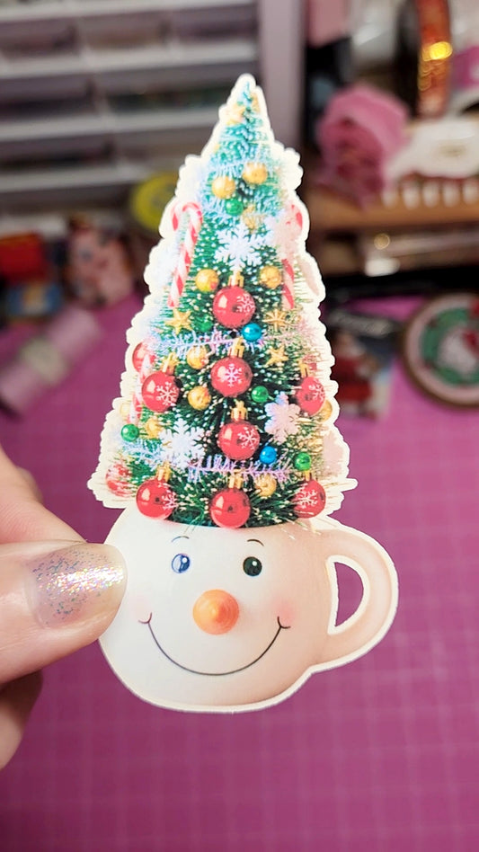 Decorative Christmas tree on a snowman-shaped cup with colorful beads against a blurred background.