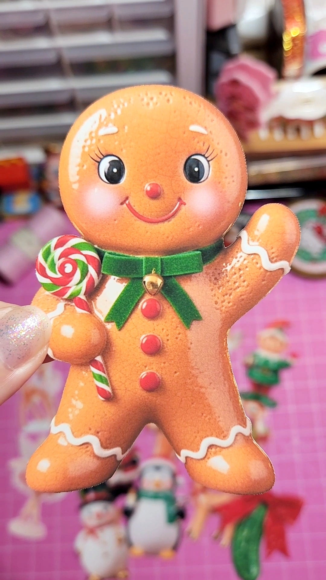 Gingerbread man toy with a lollipop held by a hand against a blurred background