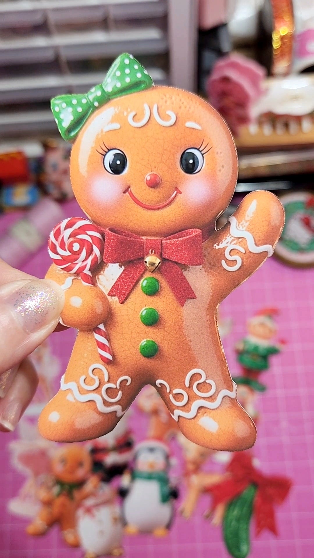 Decorative gingerbread man figurine with a green bow and red ribbon, held against a blurred background.
