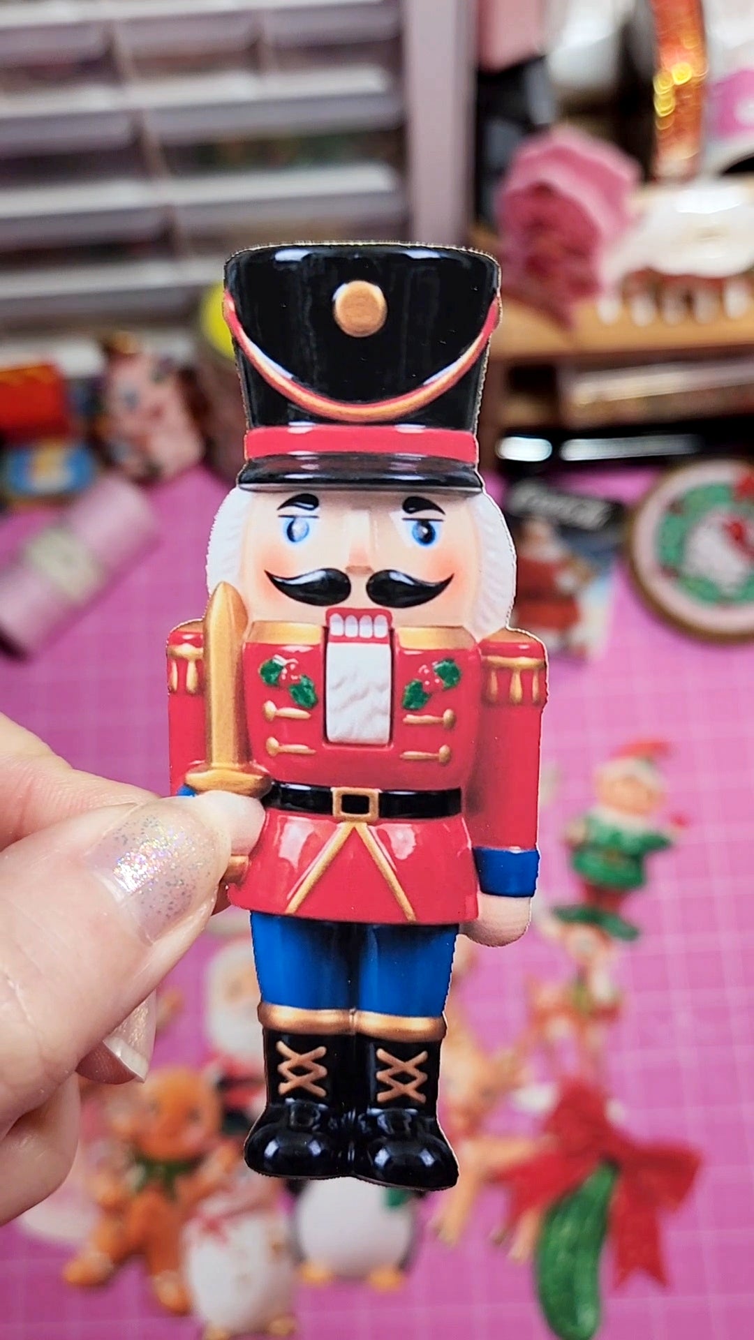 Nutcracker figurine held in a hand with a colorful, blurred background