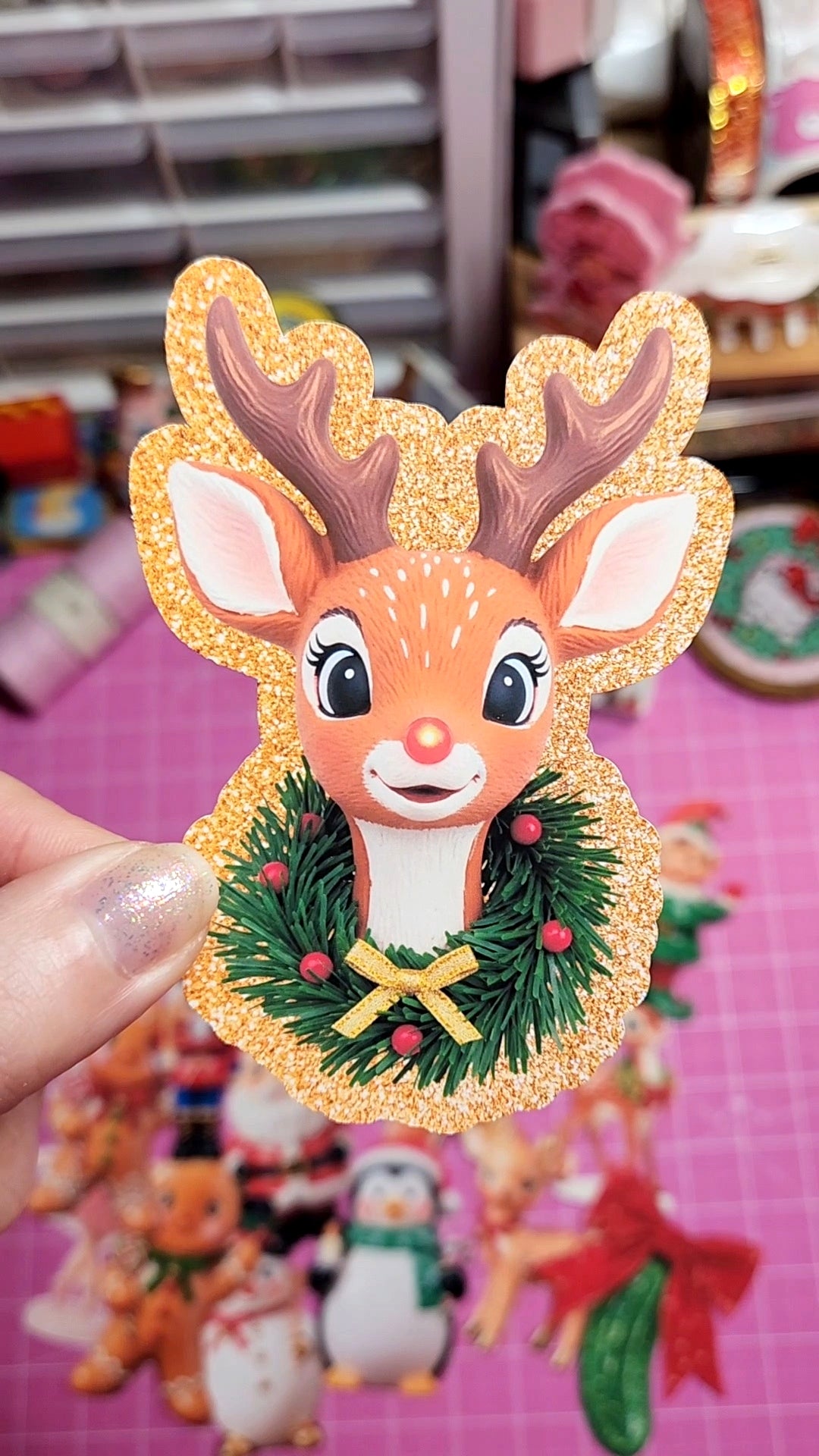 Decorative reindeer ornament with a wreath on a pink background