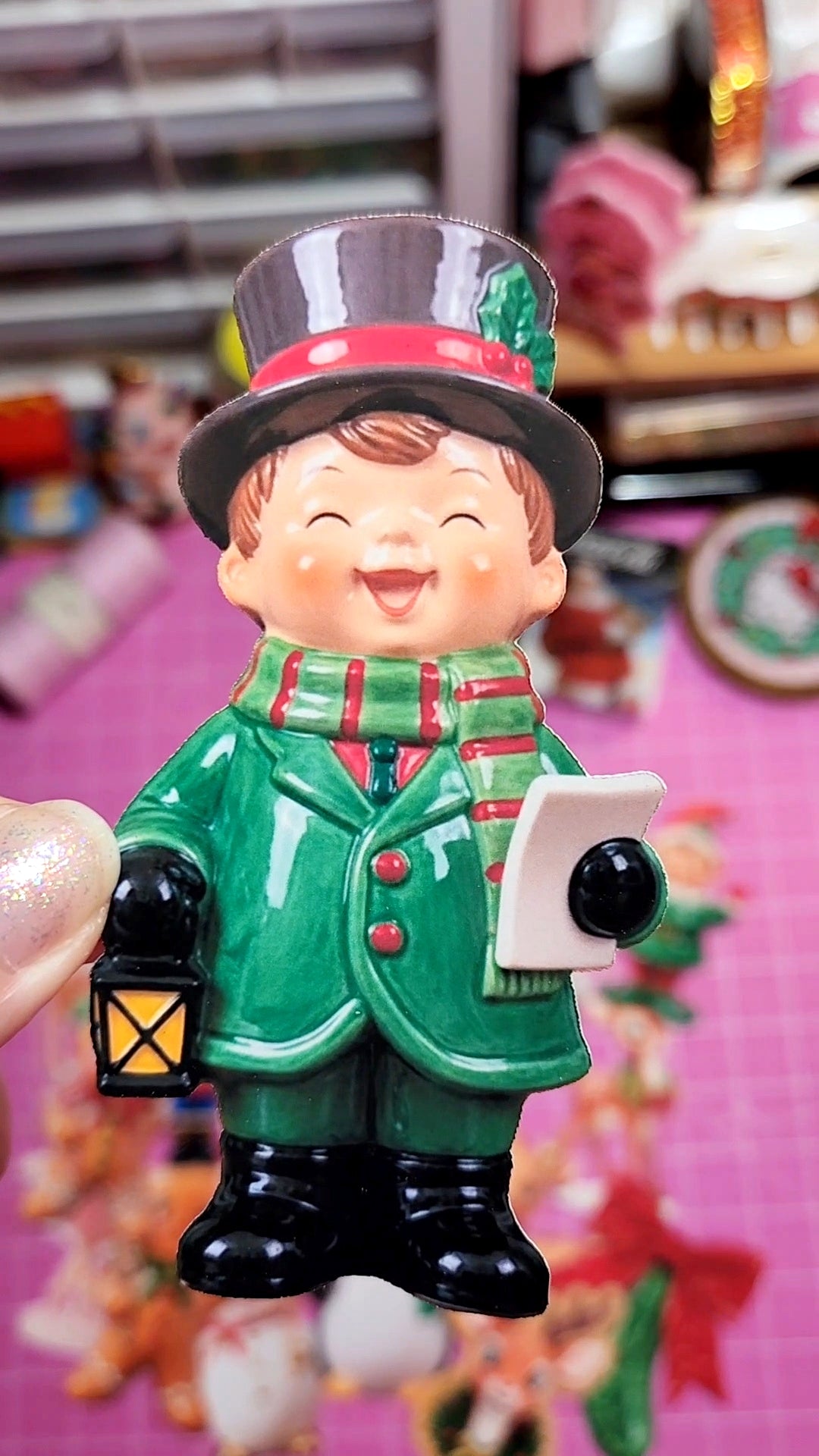 Small figurine of a character in a green coat and hat holding a lantern, with a colorful background.
