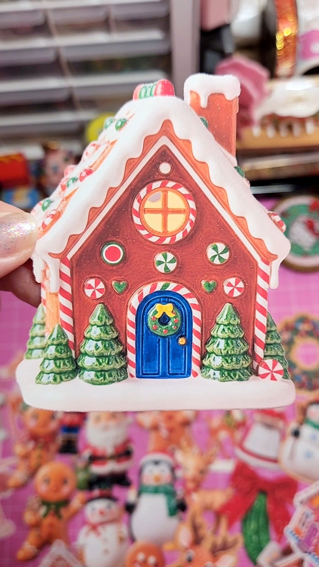 Decorative gingerbread house with a blue door held in front of a colorful background.