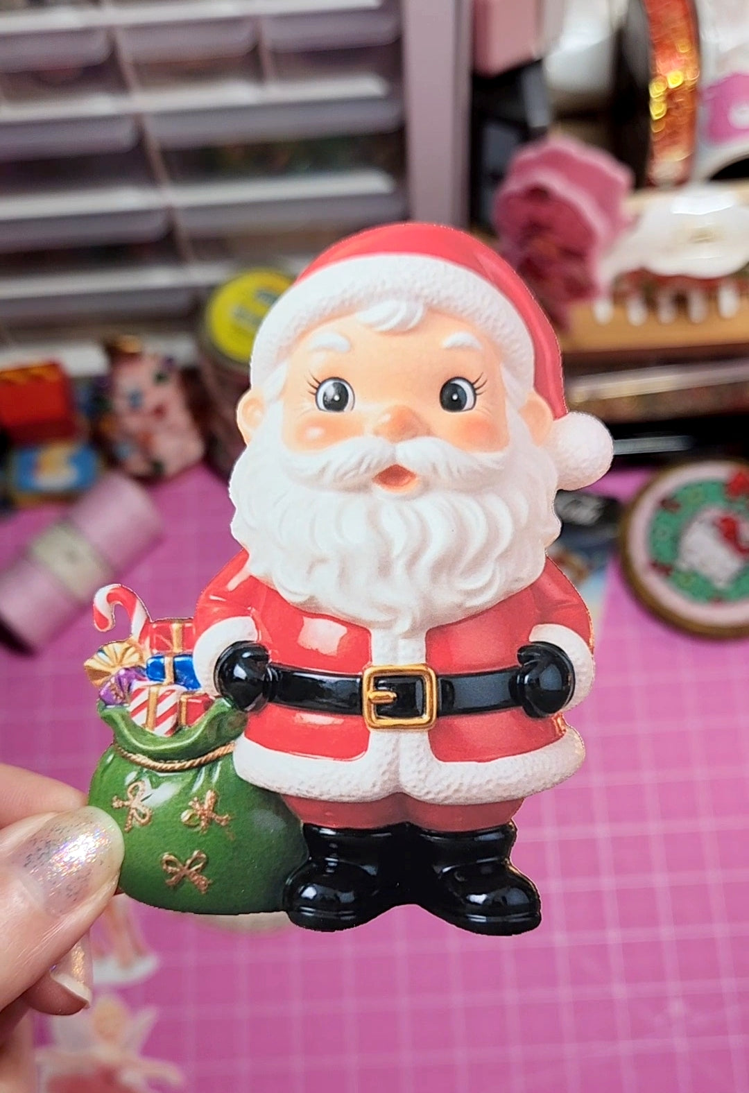 Santa Claus figurine held by a hand with a blurred background