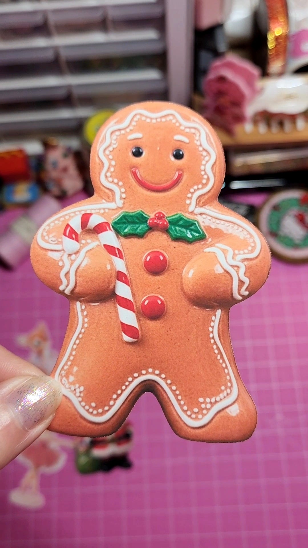 Gingerbread man cookie with candy cane and holly leaves held against a colorful background