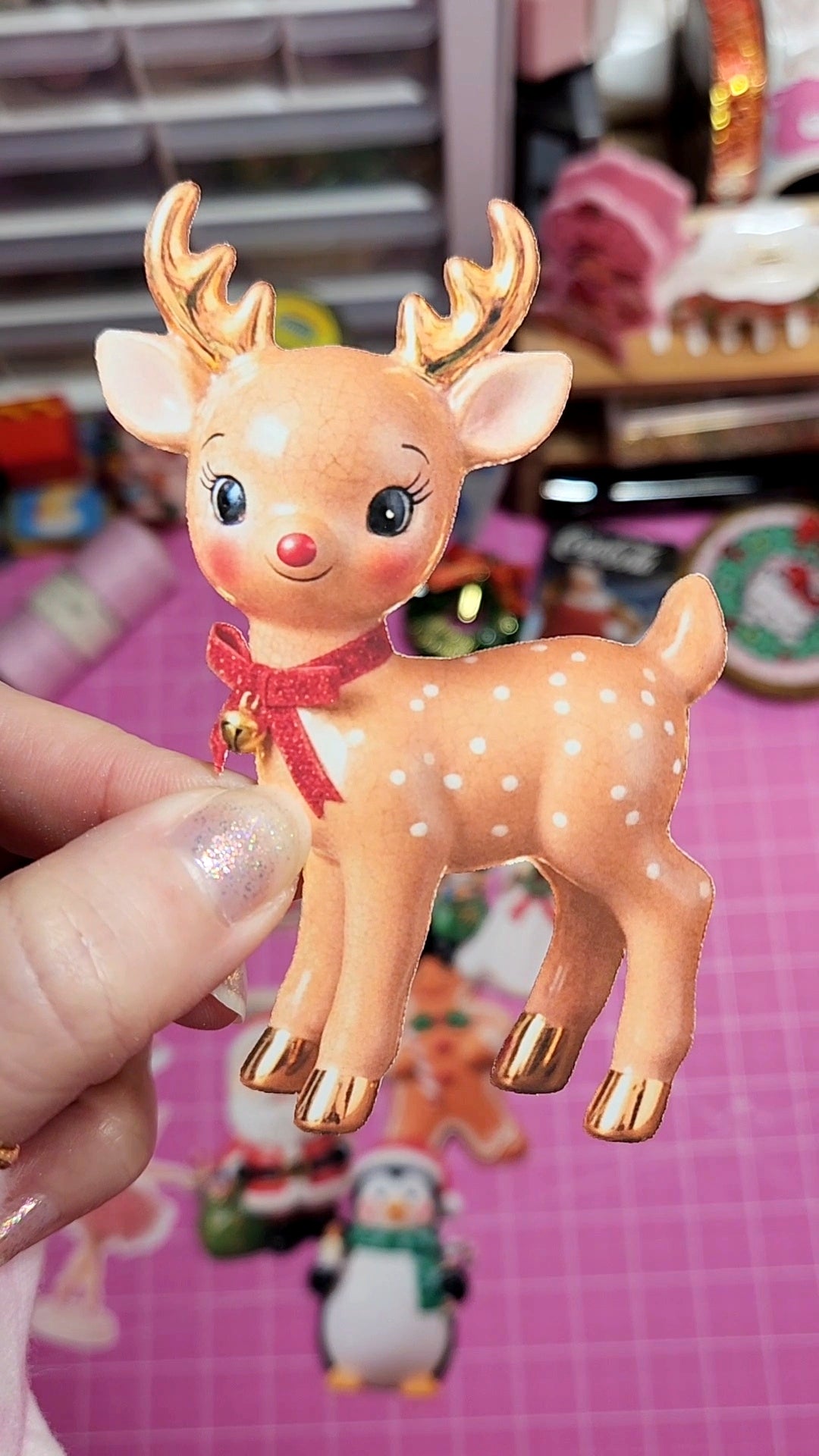 Small deer figurine held by a hand with a pink background