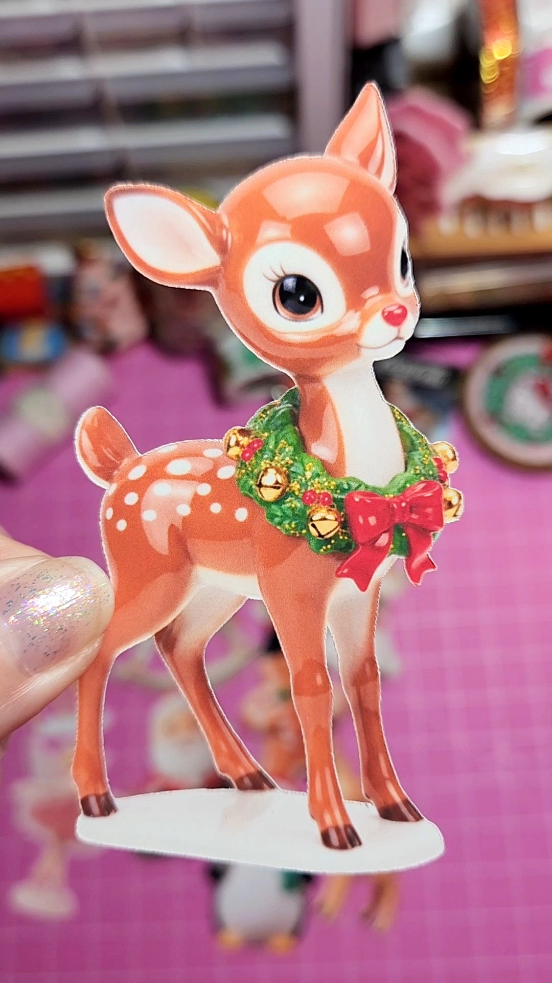 Animated deer figurine with a wreath on a pink background