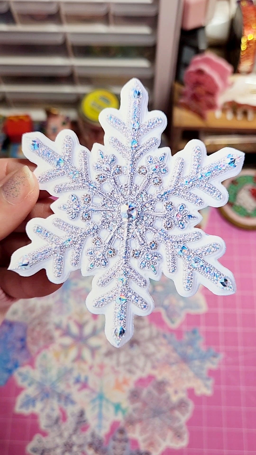 Decorative snowflake with glittery details held by a hand against a colorful background.