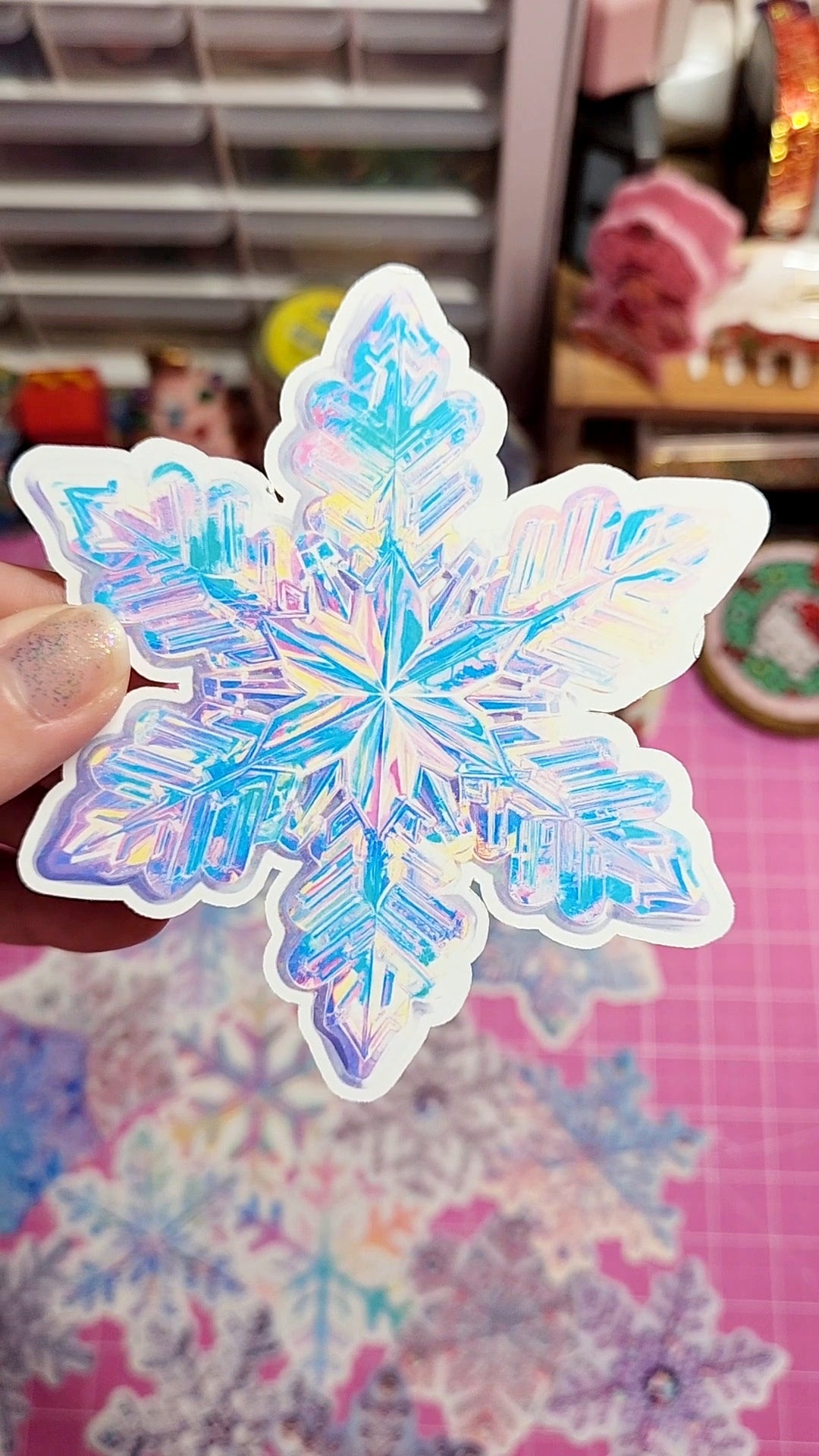 Holographic snowflake sticker held by a hand with a colorful background