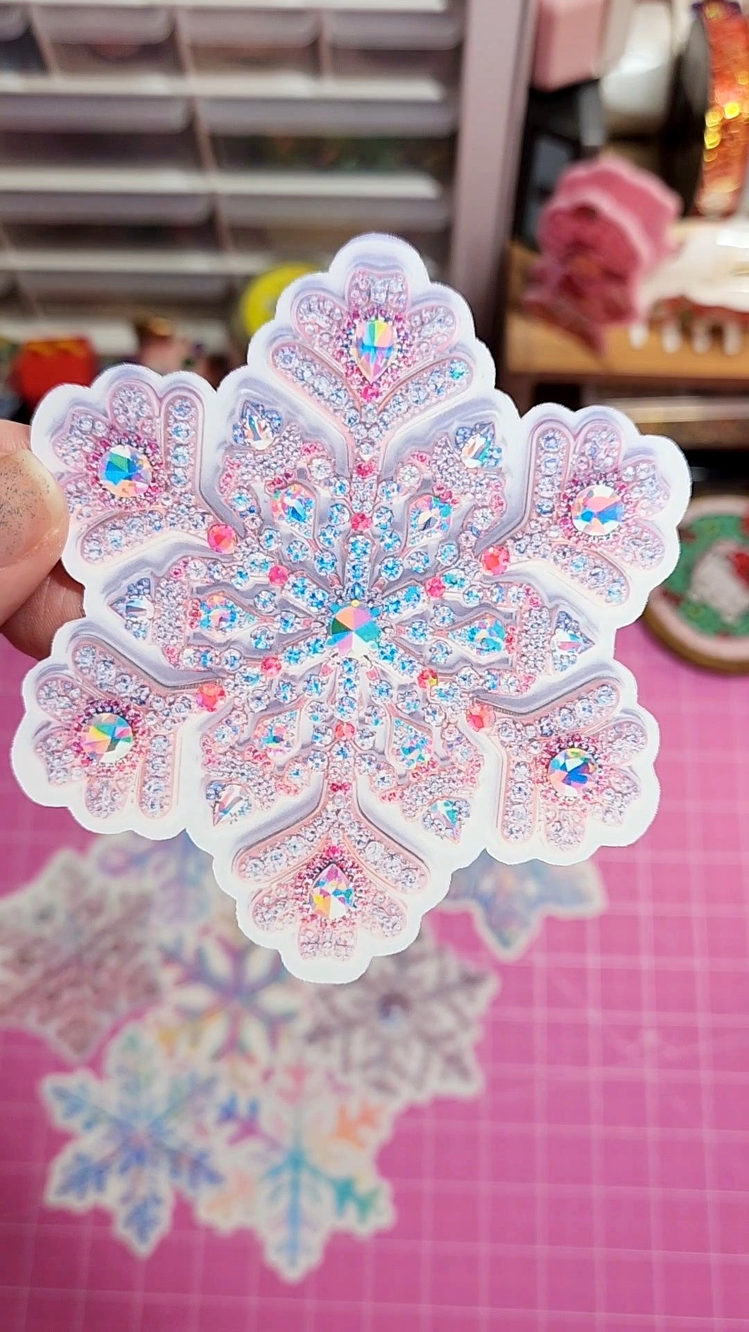 Decorative sticker with a colorful, intricate design held over a pink surface.