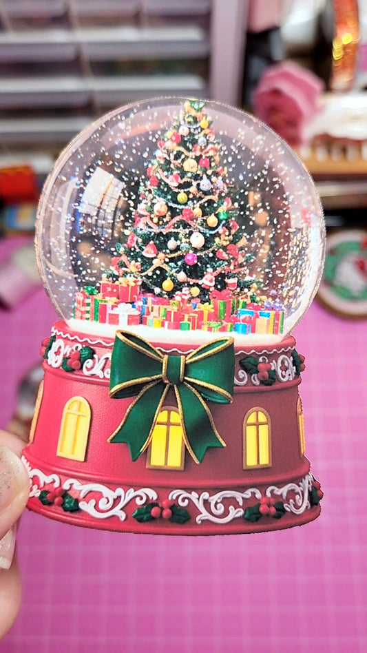 Decorative Christmas snow globe with a tree and presents on a pink background