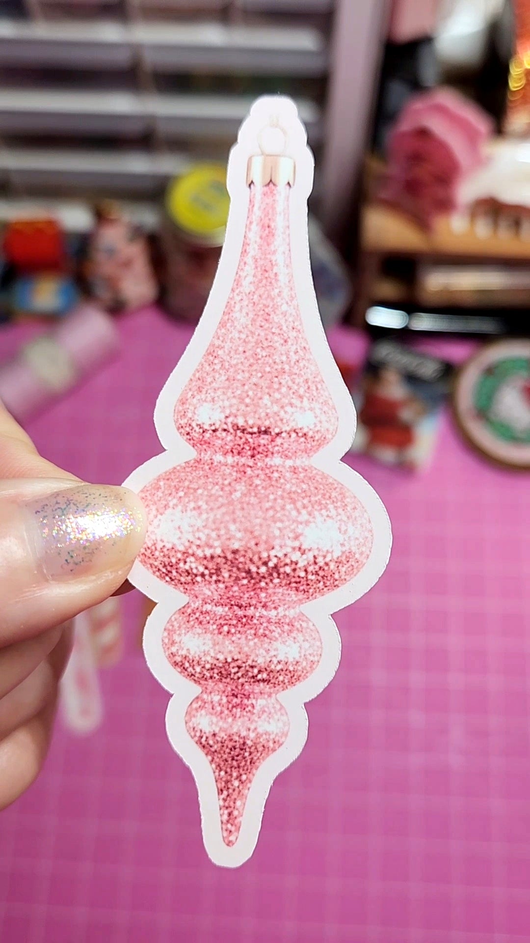 Decorative pink and silver spire held by a hand against a blurred background