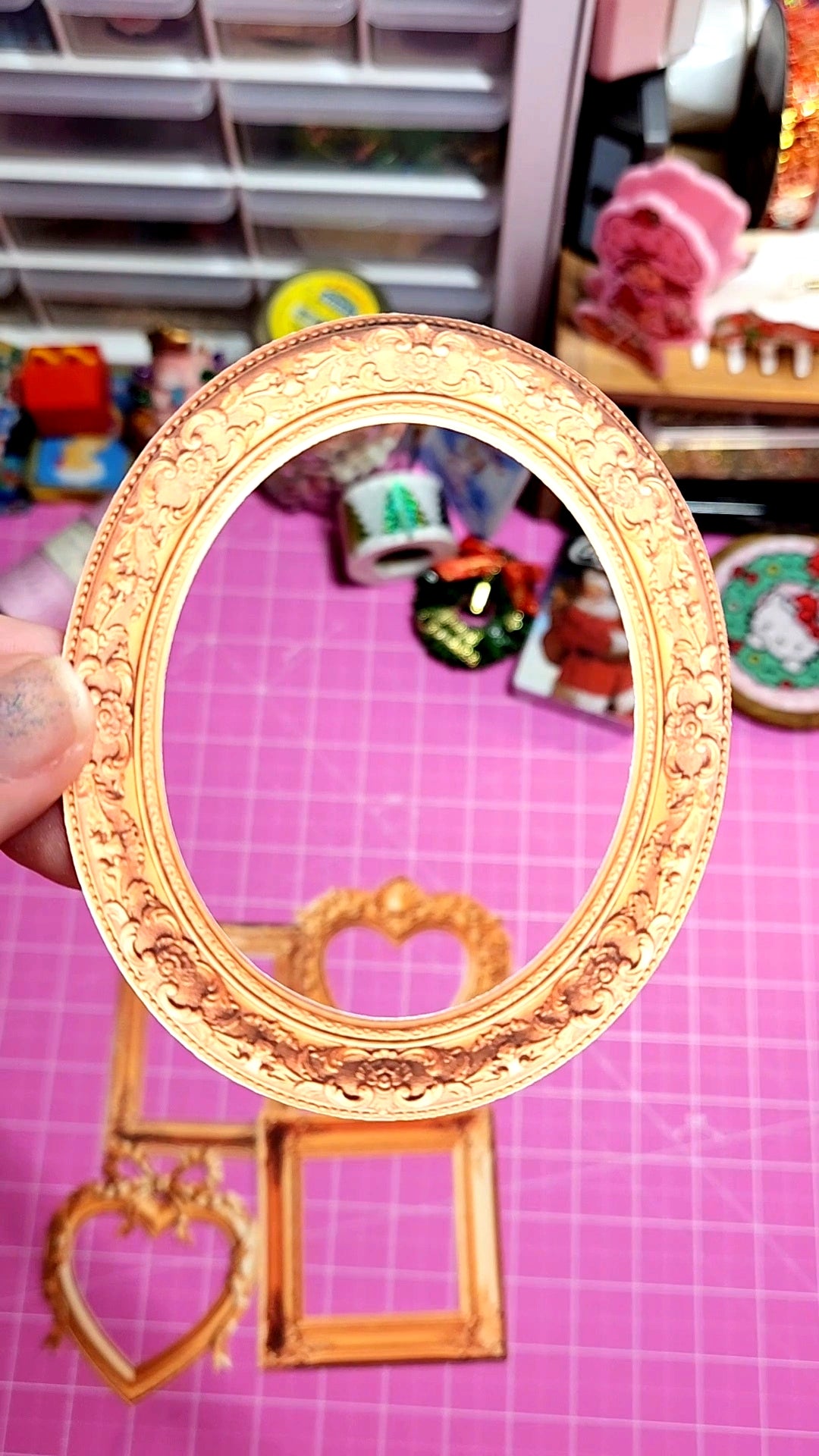 Decorative gold mirror with intricate designs on a pink grid background