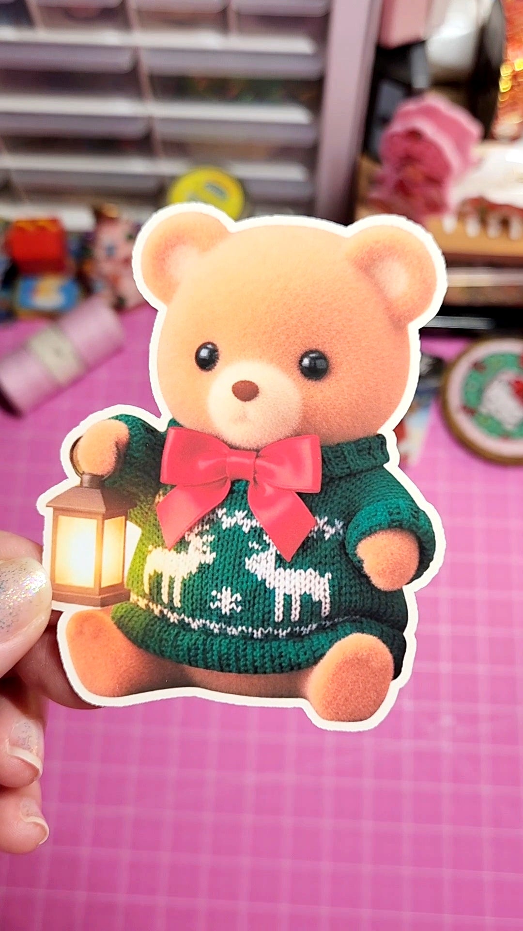 Cartoon bear with a green sweater and pink bow holding a lantern on a pink background