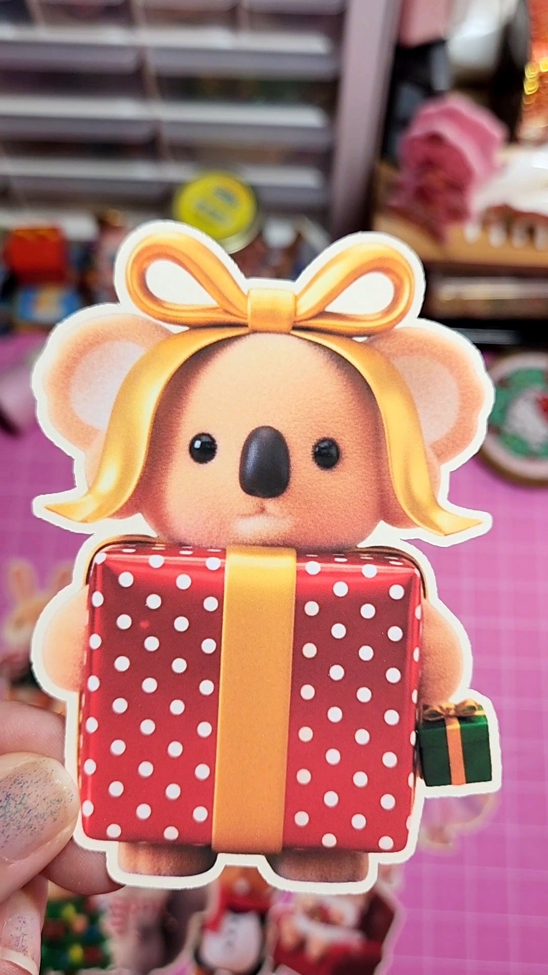 Toy figure of a bear with a bow and gift box on a pink background
