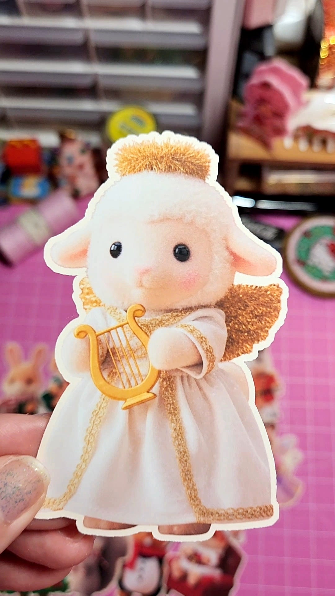 Plush toy angel held by a hand with a colorful background