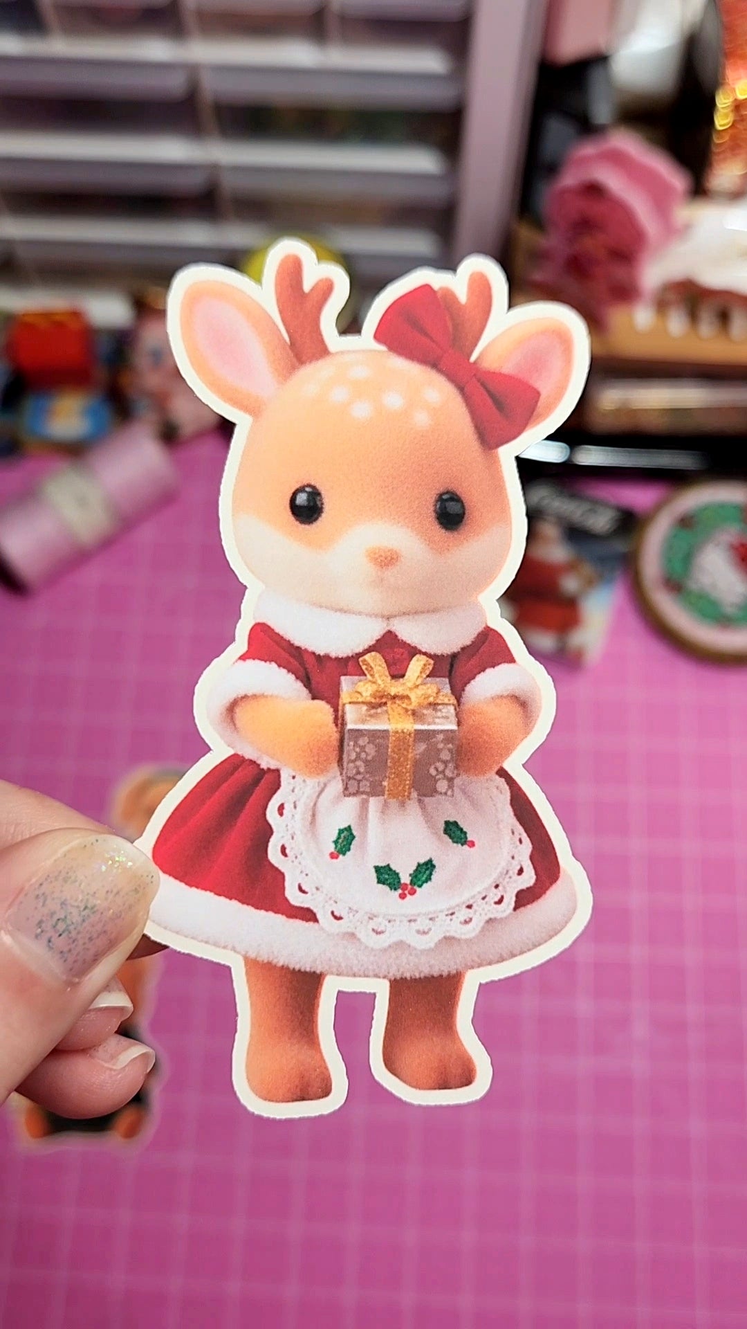 Cartoon deer character holding a gift on a pink grid background