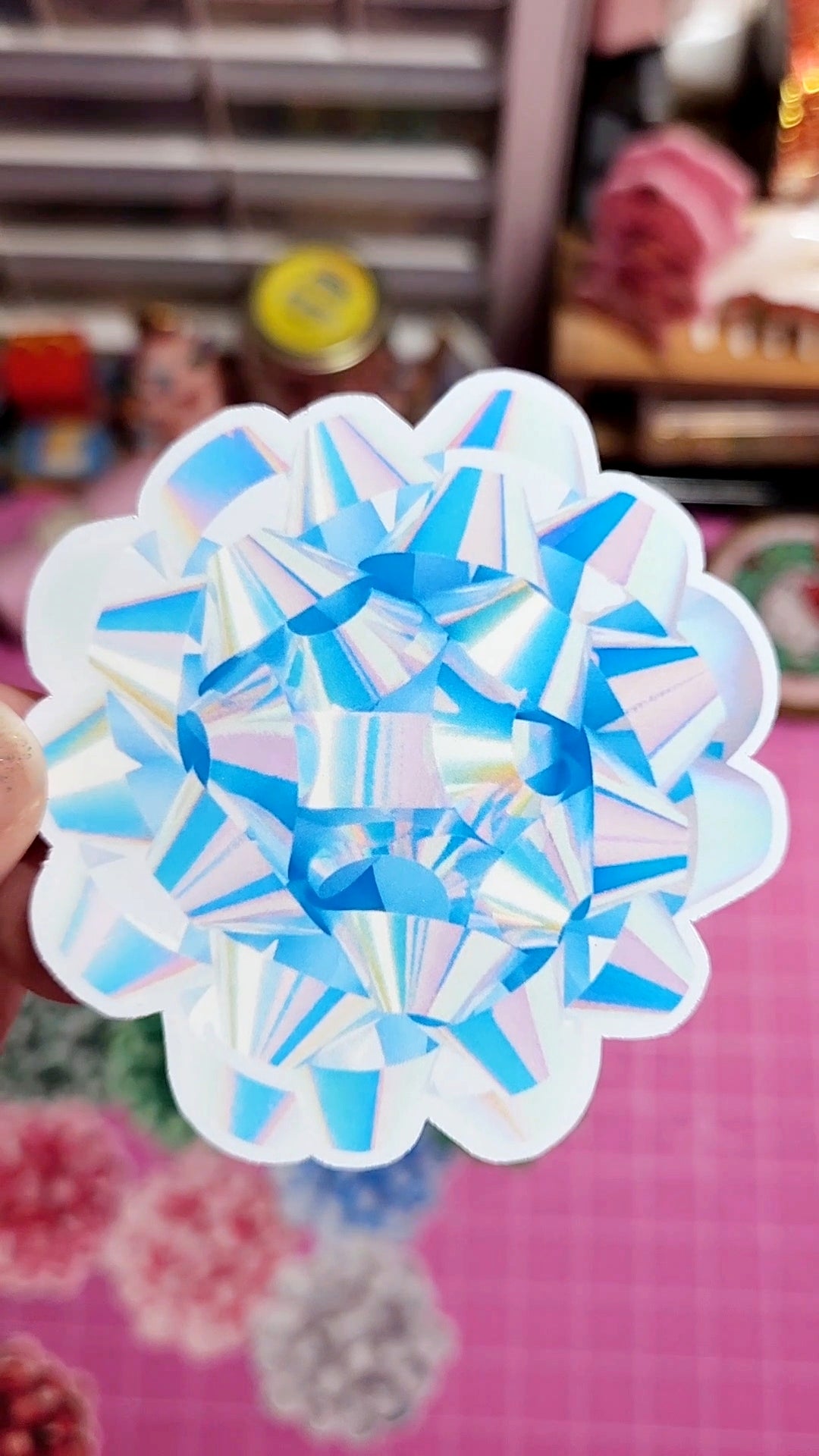 Decorative paper snowflake with blue and white patterns on a pink background