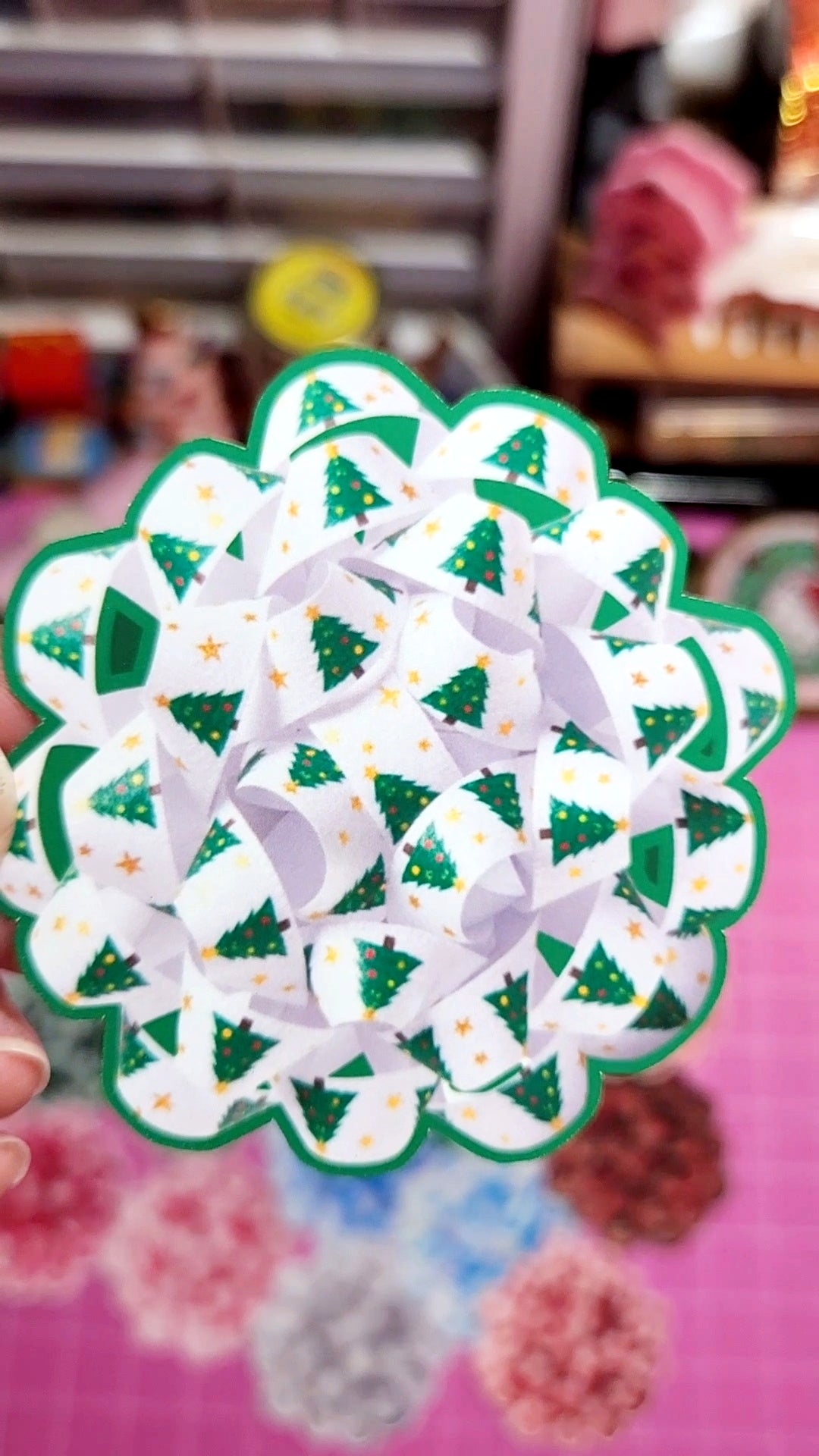 Decorative paper craft with green and white design on a pink background